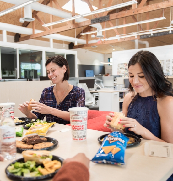 Two women smiling eating Capriotti's sandwiches