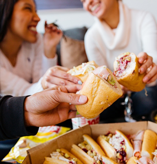 people holding sandwiches