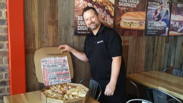 Capriotti's franchise partner Heath Mitchem posing with sandwiches